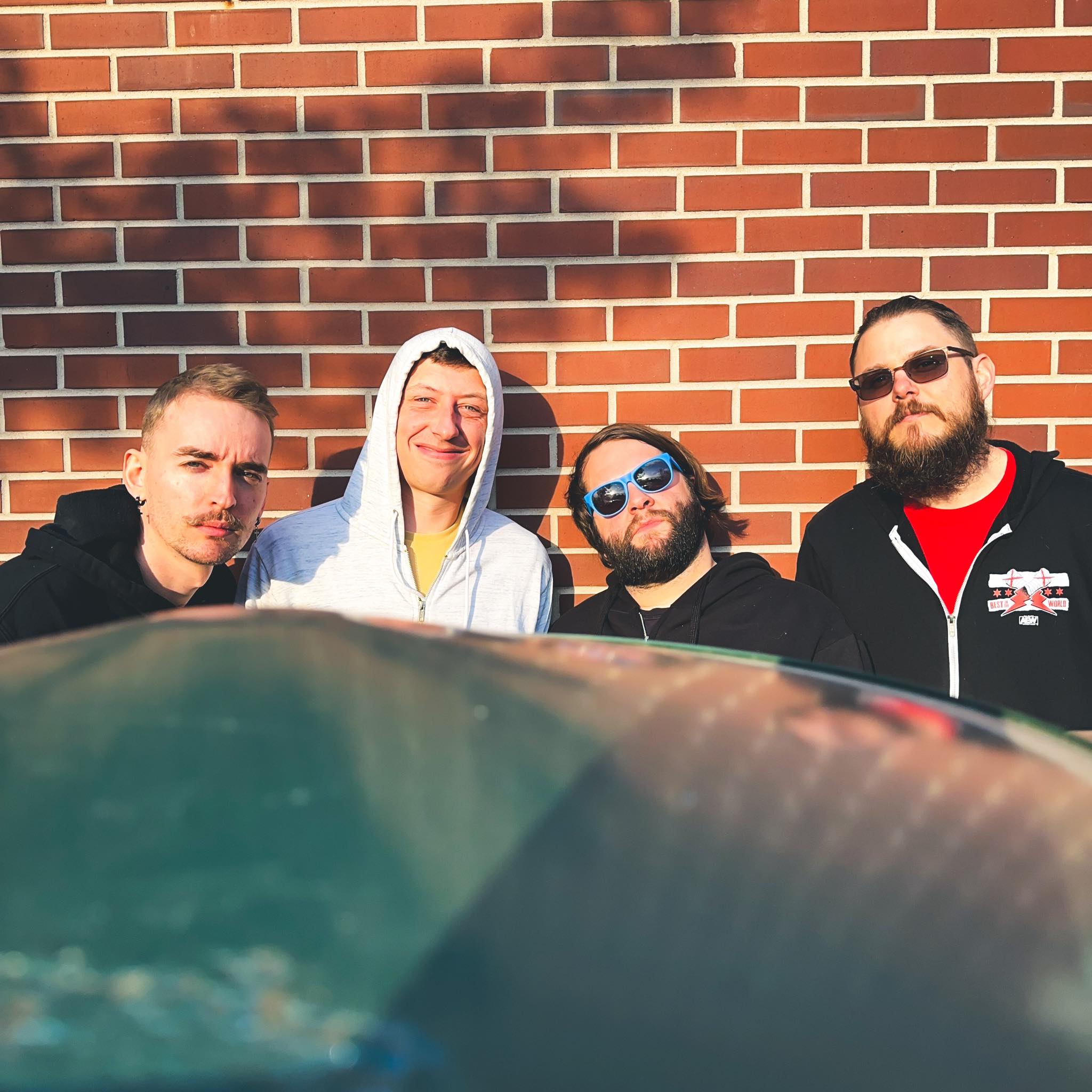 Band members pose against a brick wall