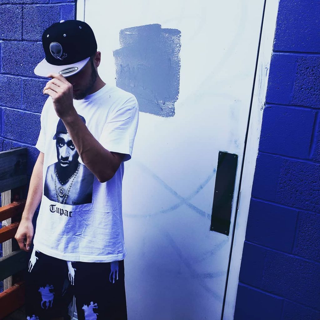 Big Sherm is pictured wearing a baseball cap in a blue room