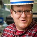 Sievert is pictured wearing a straw skimmer hat with a red white and blue stripped ribbon