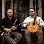 Sean and Michael Gavin sit on a staircase holding their instruments.