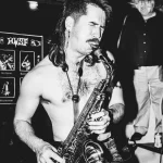 A member of Geech plays the saxophone in a black and white photo