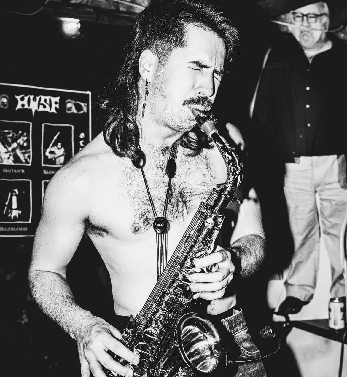 A member of Geech plays the saxophone in a black and white photo